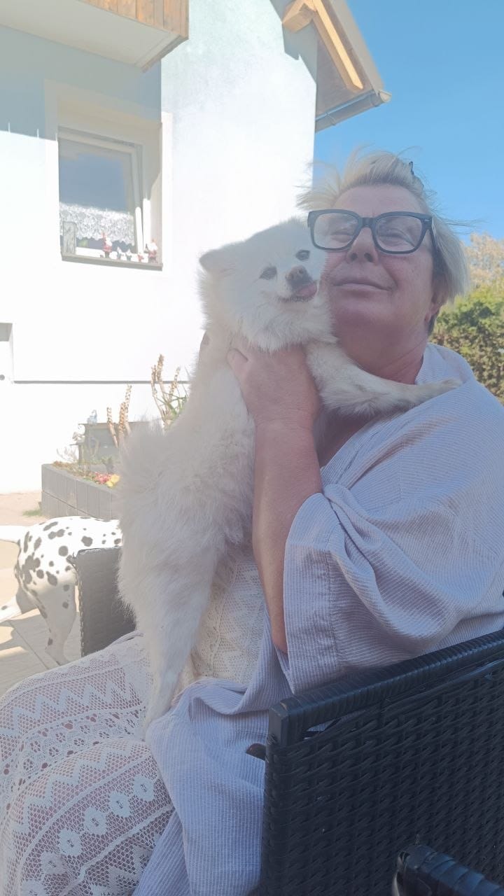 Zufriedene Kundin haelt ihren weissen Zwergspitz Bella im Arm als Testimonial fuer gesunde selbstgebackene Hunde Leckerlis