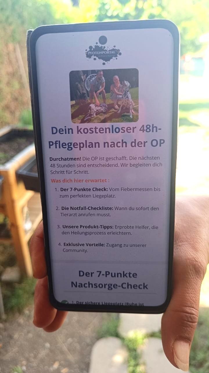 Yvonne vom Pfotenportal.at hält das Handy in die Kamera. Ein Handy mokup mit dem kostenlosen 48h Nachsorge Plan für Hunde Operationen ist zu sehen .